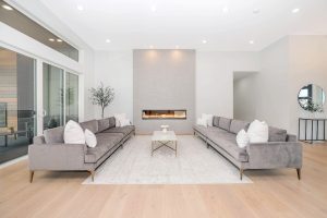A modern and inviting living room with two grey sofas, a coffee table, and a stylish fireplace, showcasing a functional